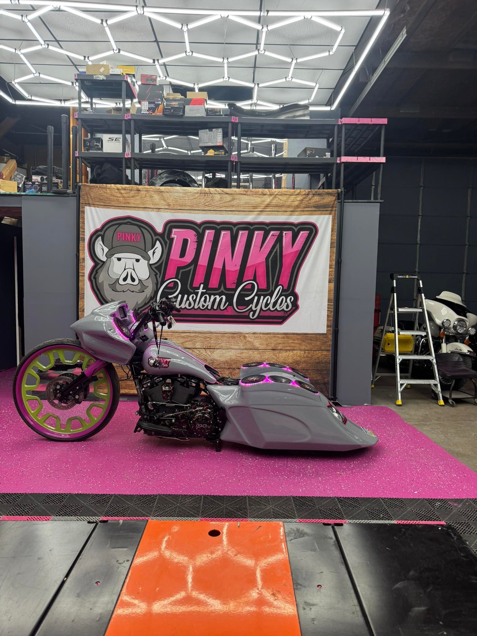 Custom motorcycle on a pink platform in a shop, logo 