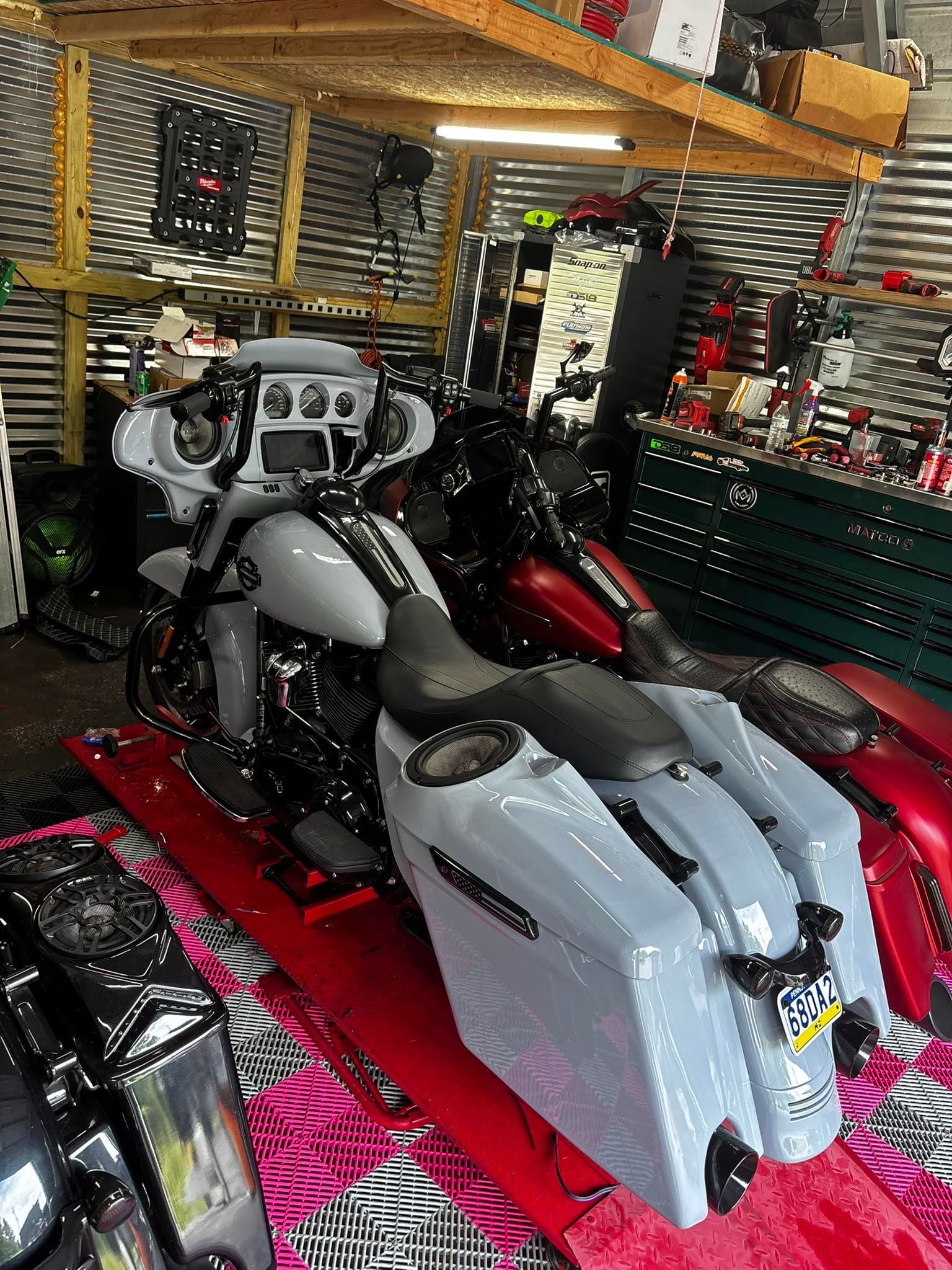 Gray motorcycle with saddlebags in a garage setting, other bikes and shelving visible.