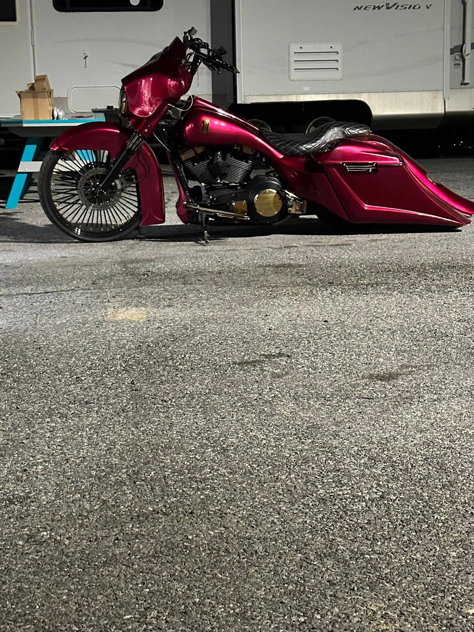 Customized magenta Harley-Davidson motorcycle parked on asphalt.