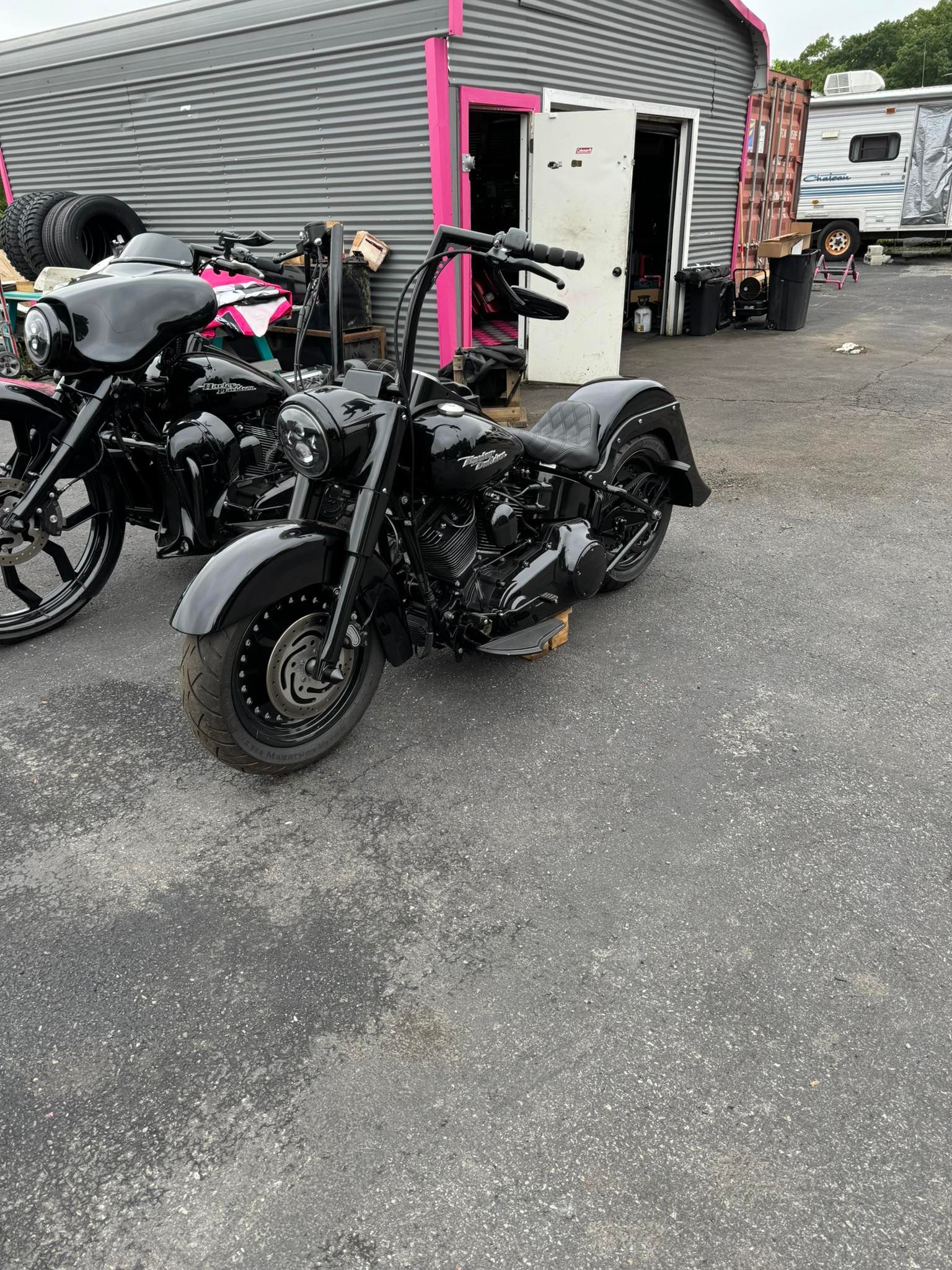 Black motorcycle parked outside a shop with another bike visible.