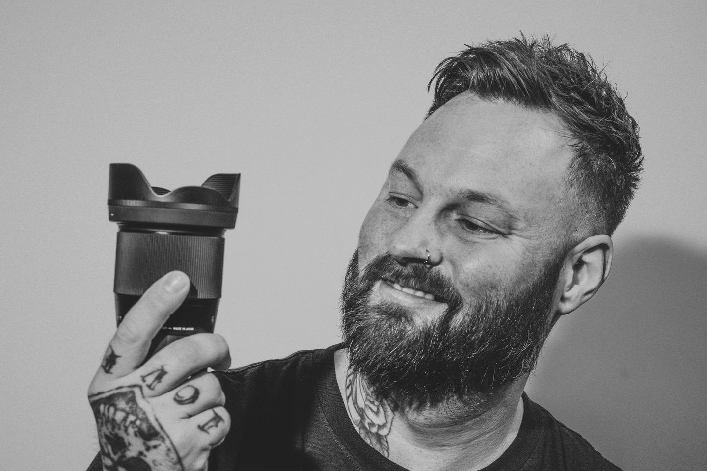 A man with a beard is holding a camera in his hand.