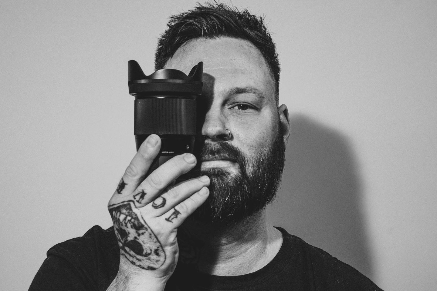 A man with a beard is holding a camera in front of his face.