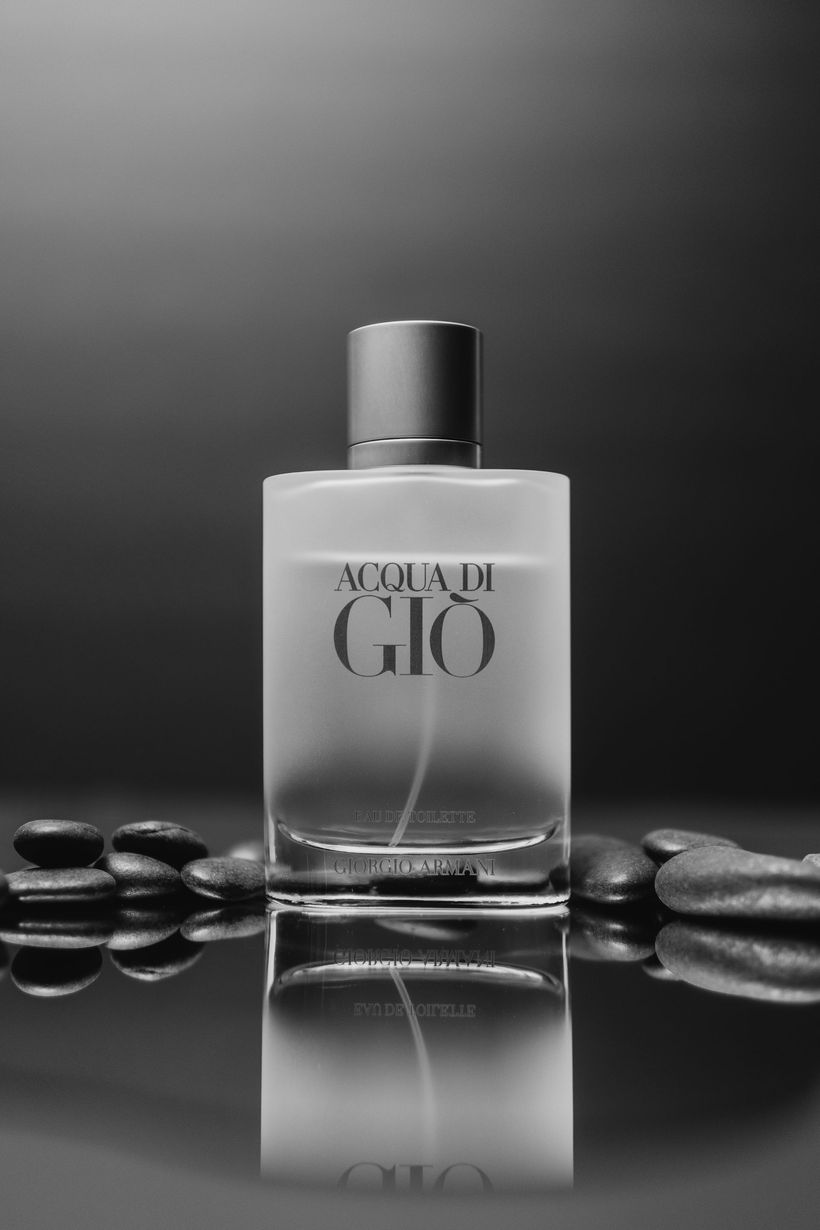 A bottle of giorgio armani acqua di gio cologne is sitting on a table surrounded by rocks.