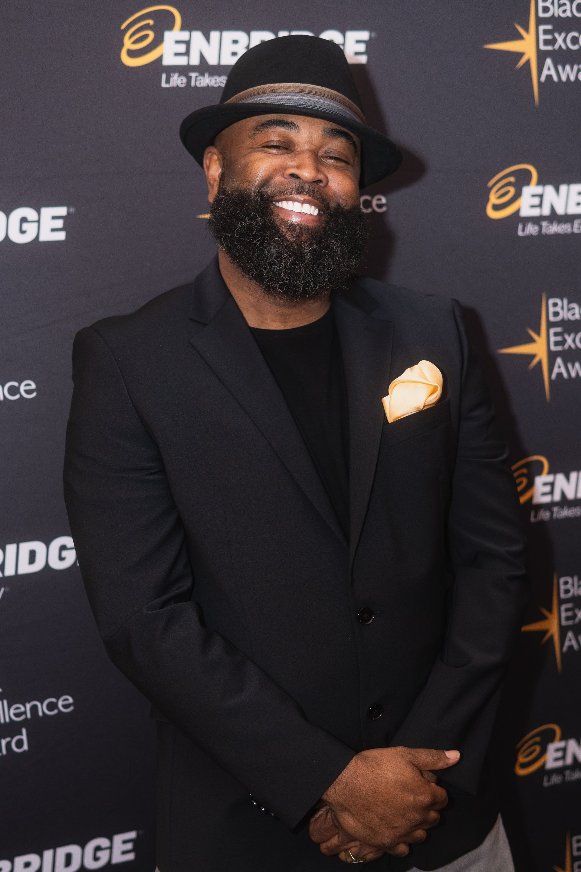 A man with a beard wearing a black suit and hat
