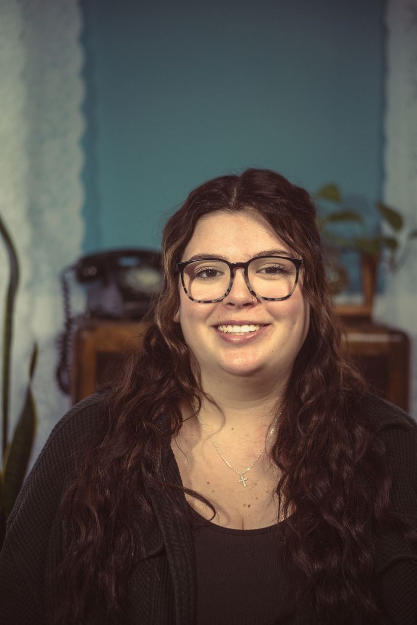 A woman wearing glasses and a black shirt is smiling for the camera.