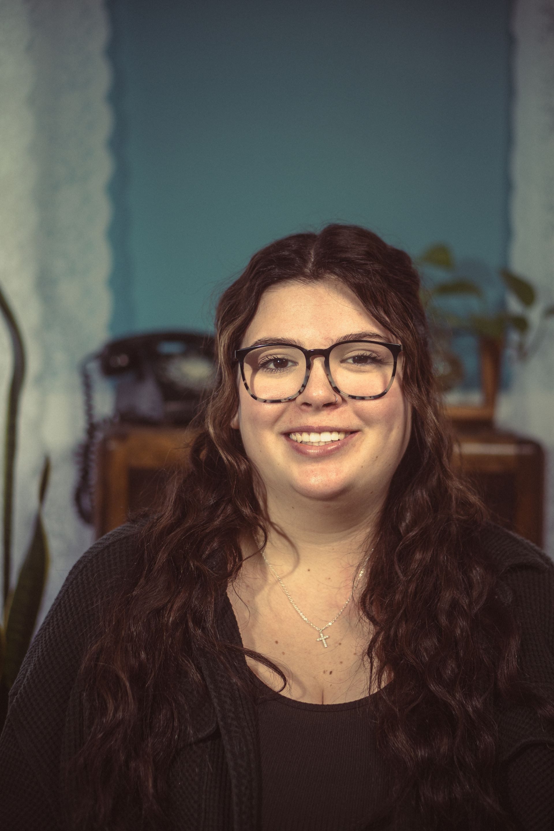 A woman wearing glasses and a black shirt is smiling for the camera.