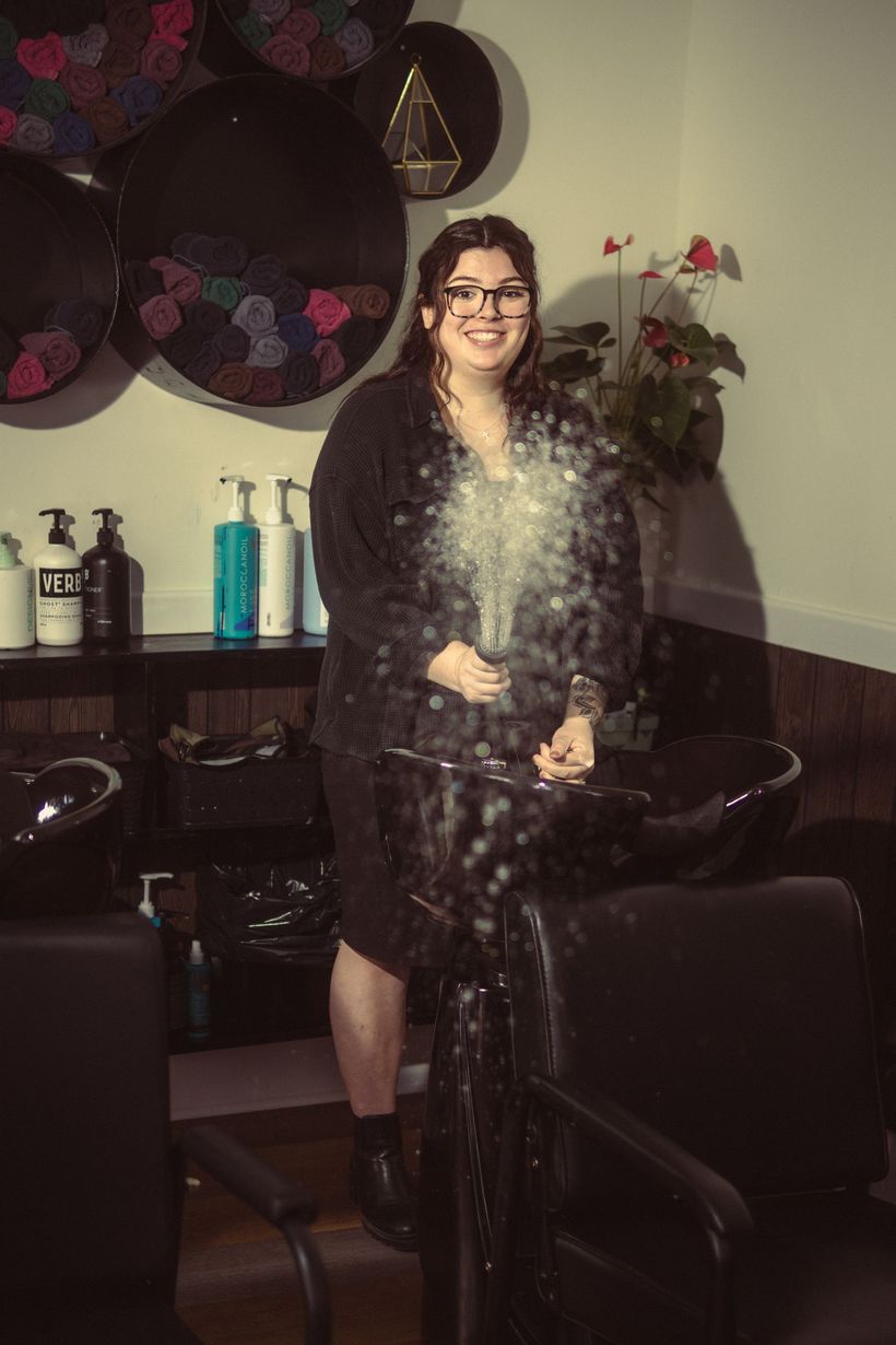 A woman is standing in front of a sink in a salon.