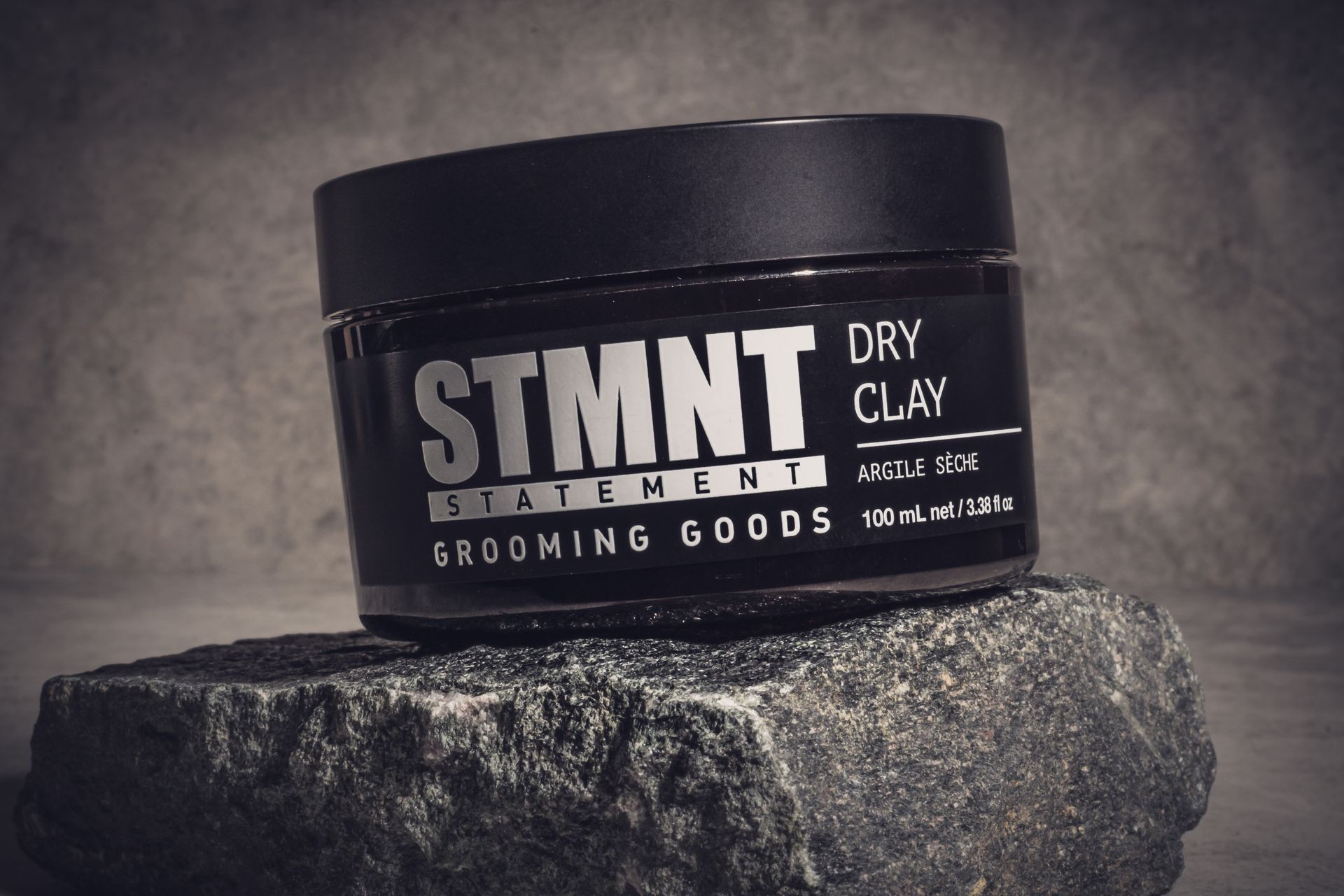 A jar of dry clay is sitting on top of a rock.