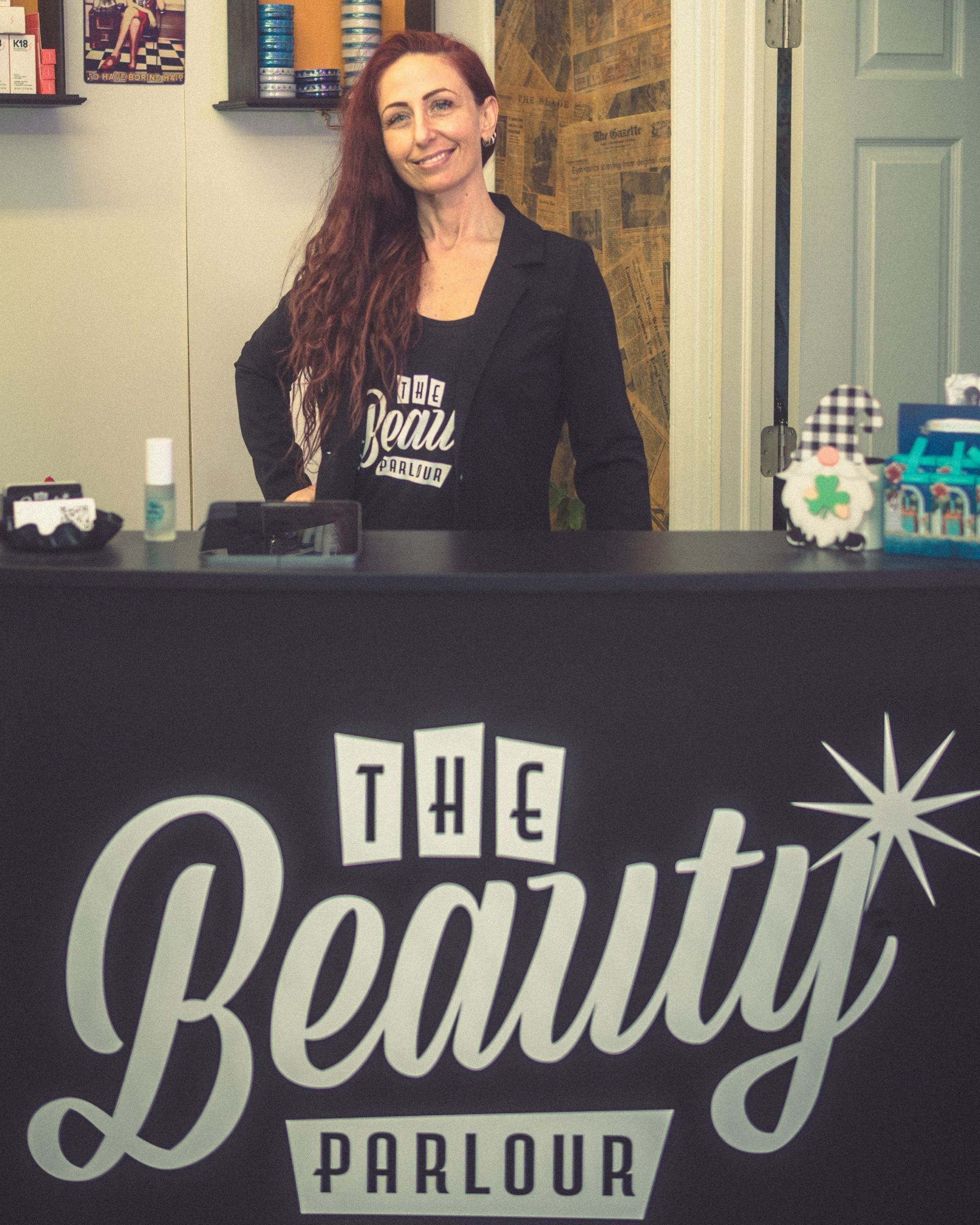 A woman stands behind a counter at the beauty parlour