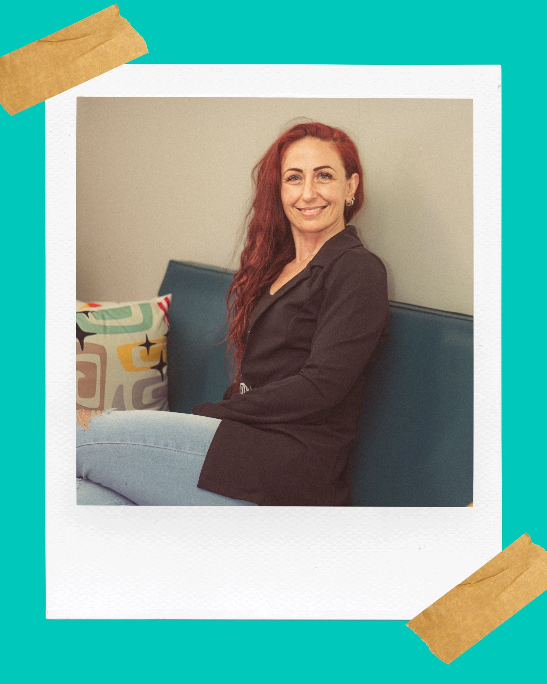 A woman with red hair is sitting on a blue couch.