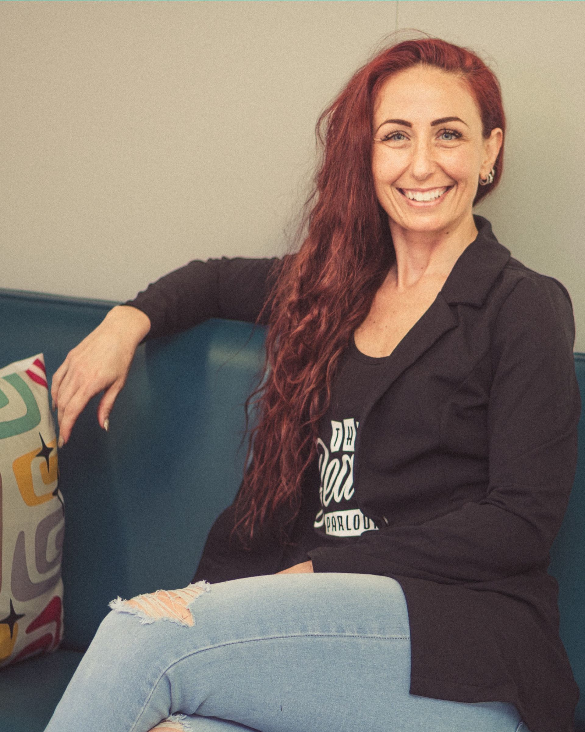 A woman with red hair is sitting on a blue couch