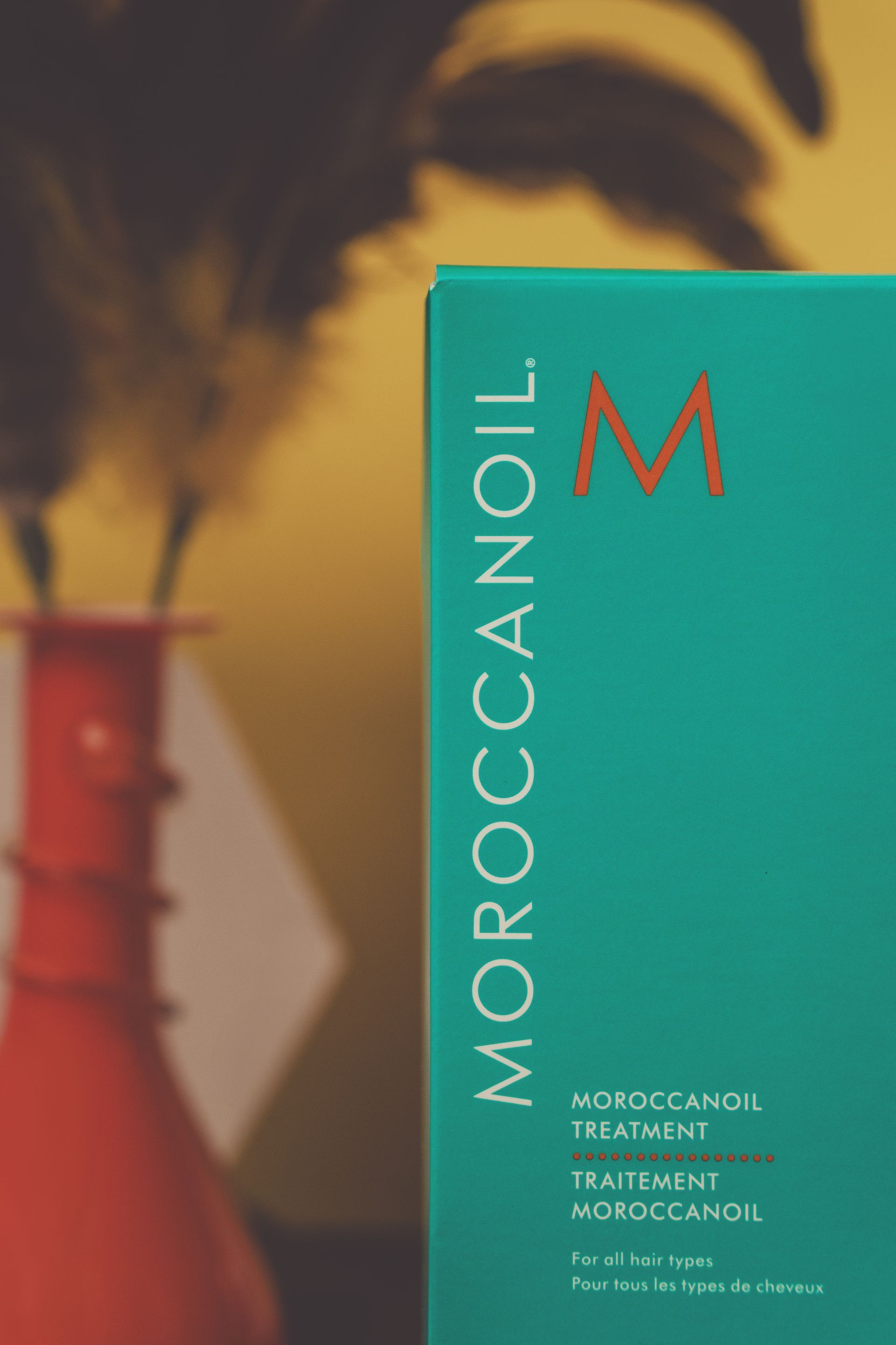 A box of moroccanoil sits next to a vase
