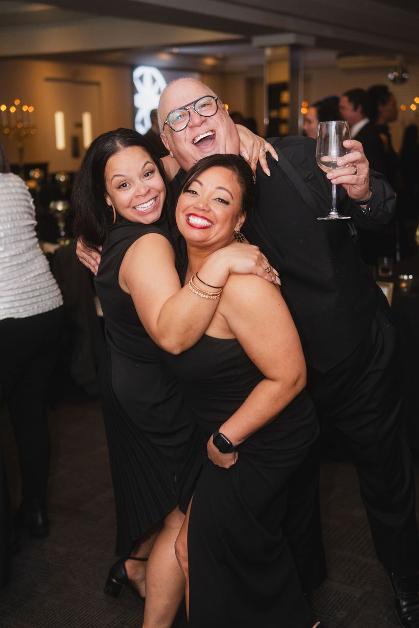 A man and two women are posing for a picture at a party.