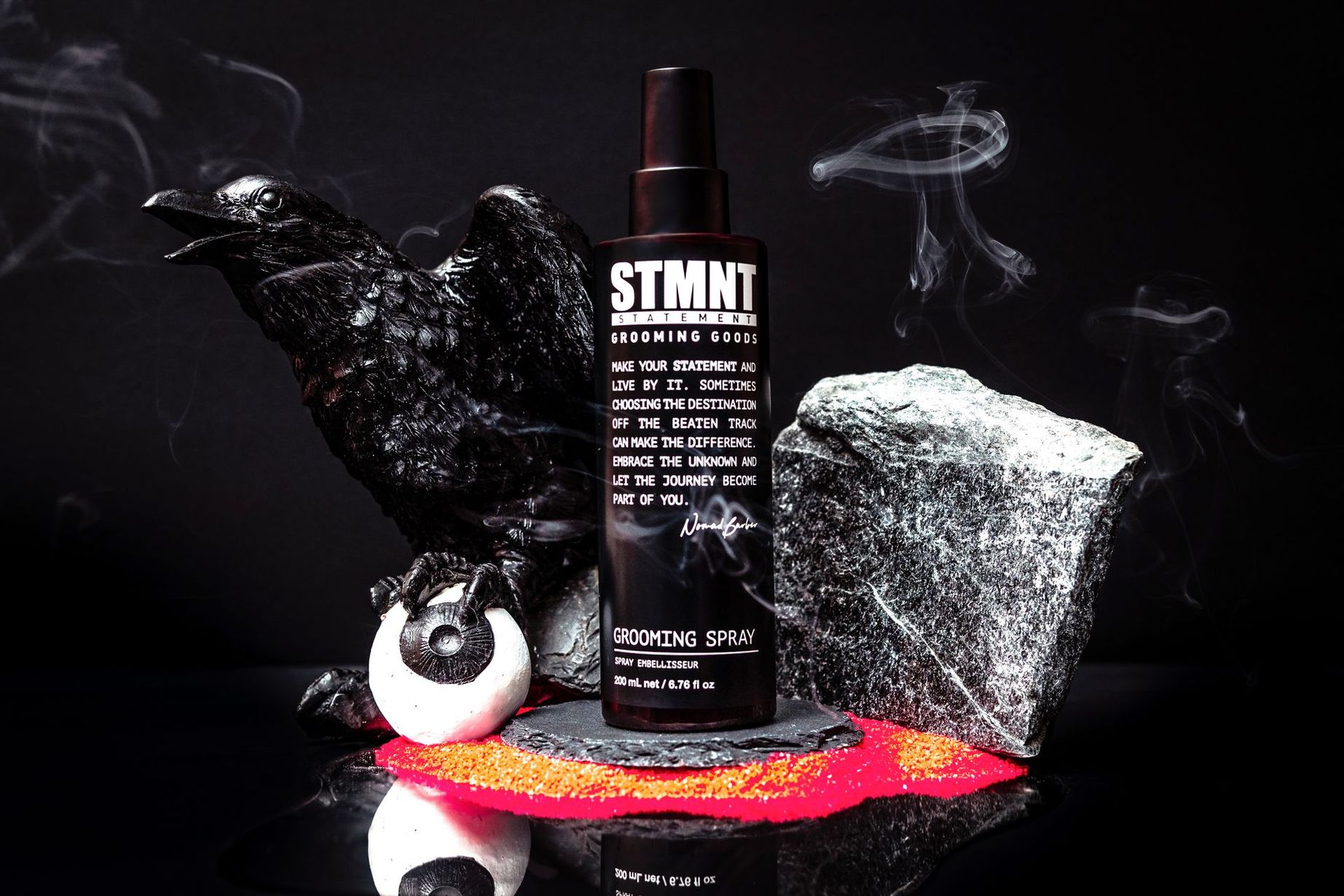 A bottle of stmnt spray is sitting on top of a rock.