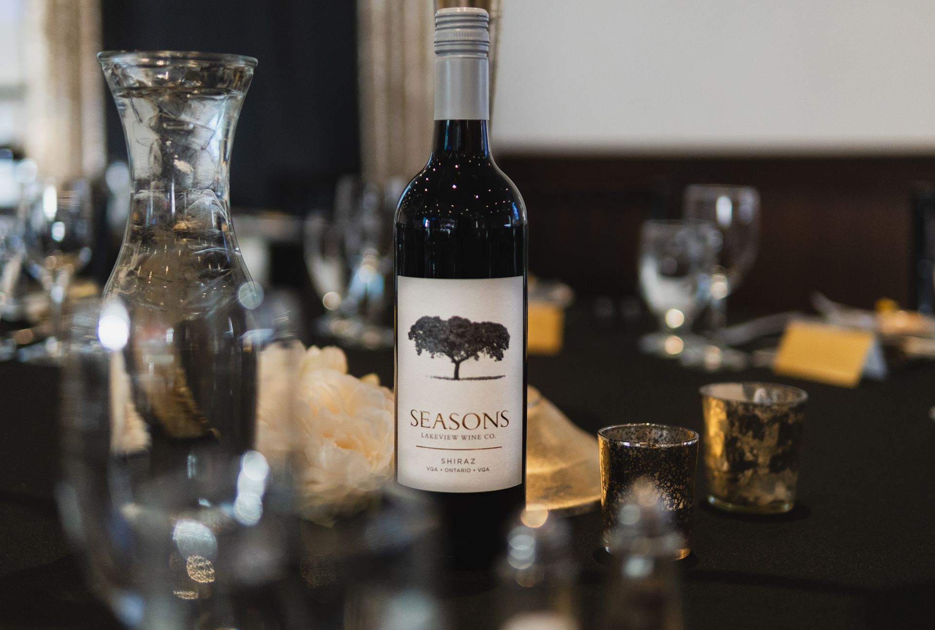 A bottle of wine is sitting on a table next to a vase.