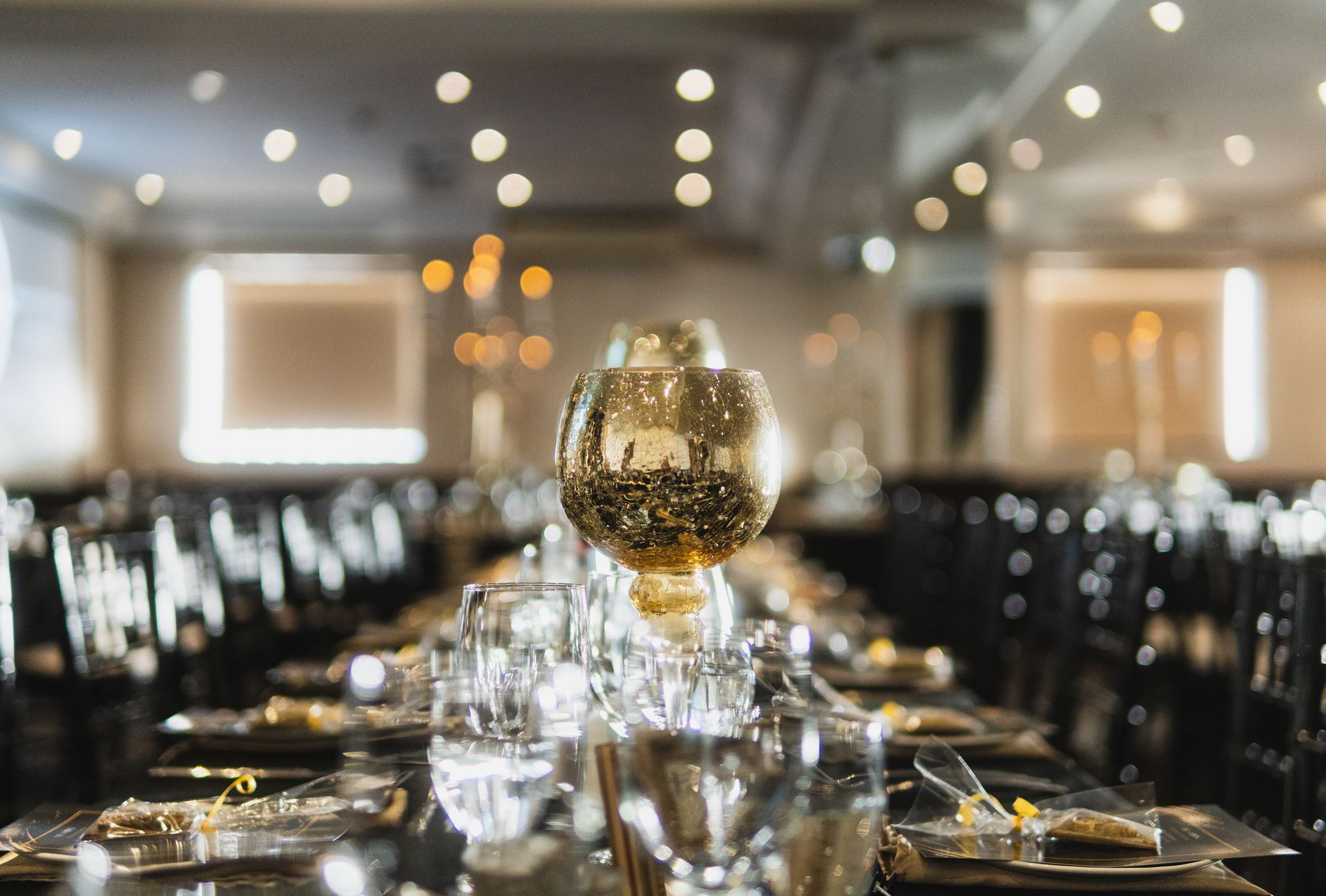 A long table with plates , glasses , and a vase on it.