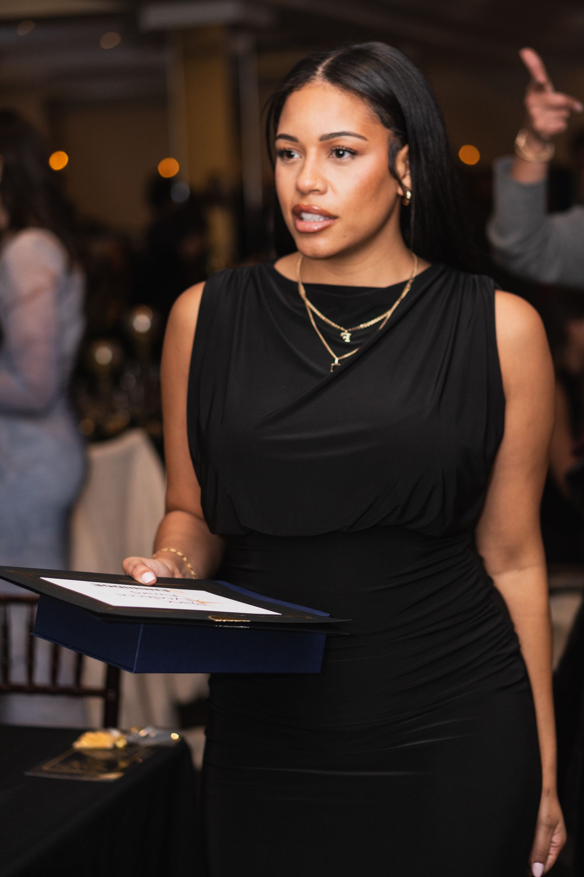 A woman in a black dress is holding a tray of food.
