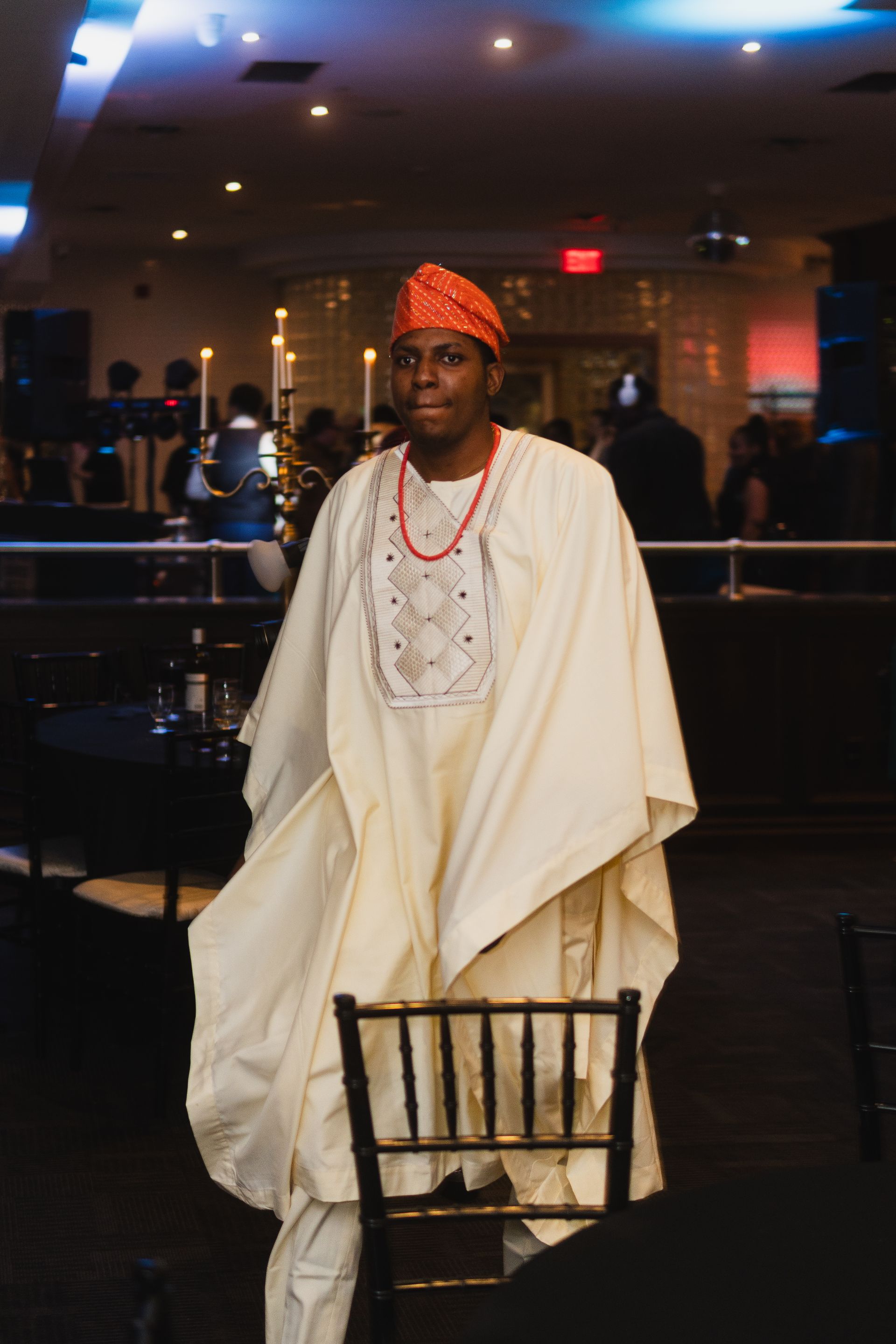 A man in a white robe is standing next to a chair in a room.
