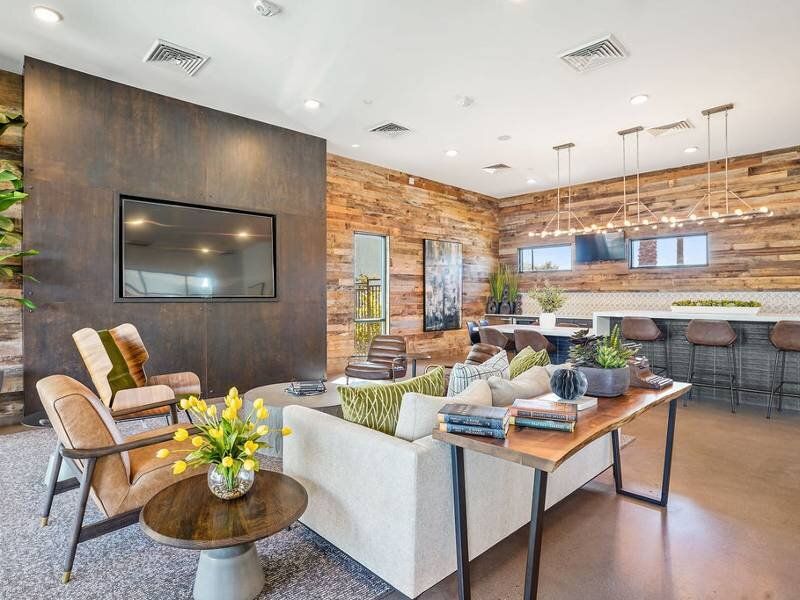 Modern apartment community lounge with wood accent walls, seating, and a bar area.
