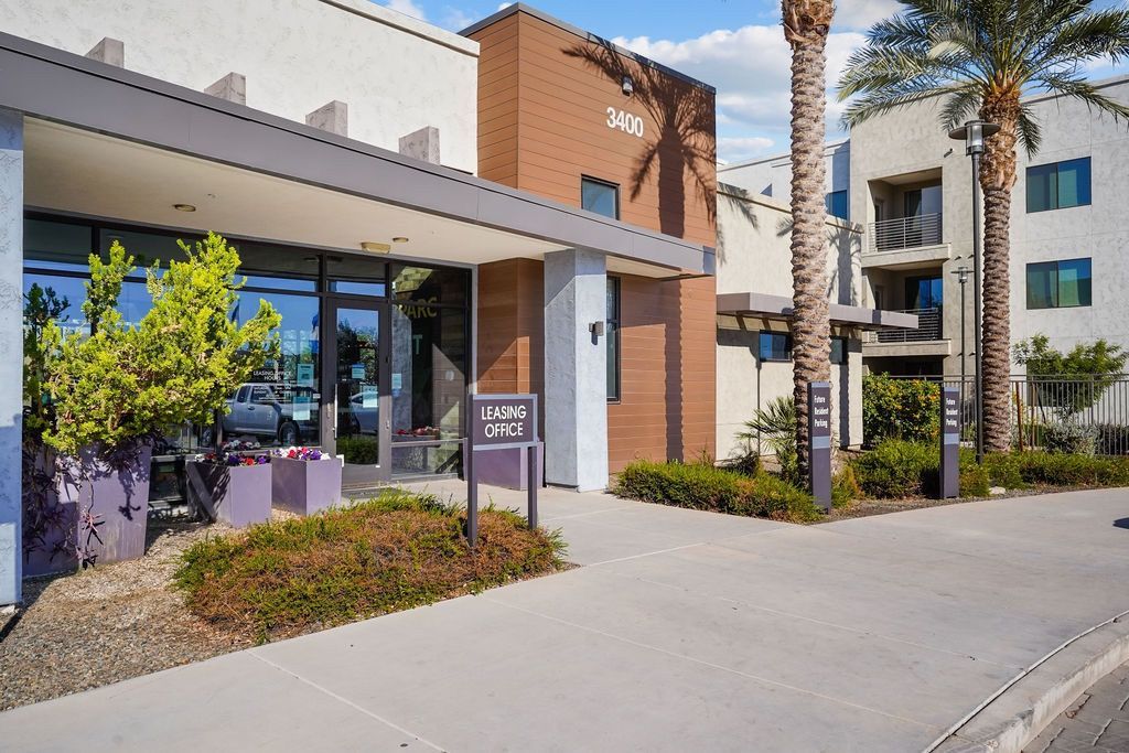 Exterior view of a modern apartment complex with leasing office entrance and signage.