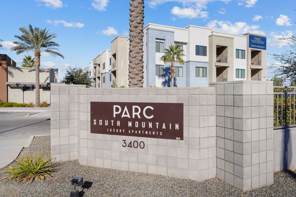 Entrance sign for Parc South Mountain Luxury Apartments with a modern building and palm trees in the background.