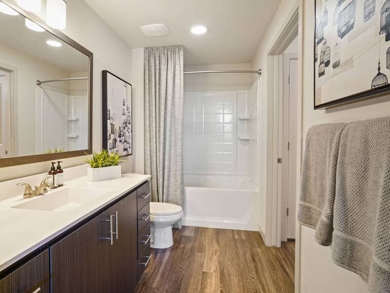 Modern apartment bathroom with double-sink vanity, toilet, and tub/shower.