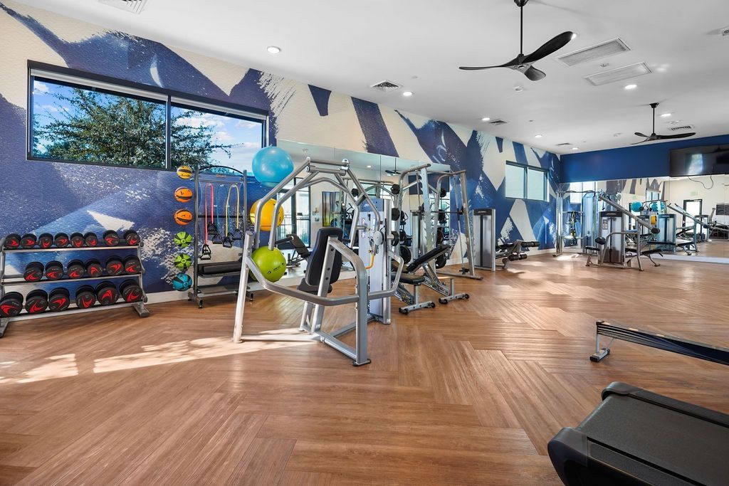 Bright fitness center with free weights, weight machines, and cardio equipment in a mural-laden room.