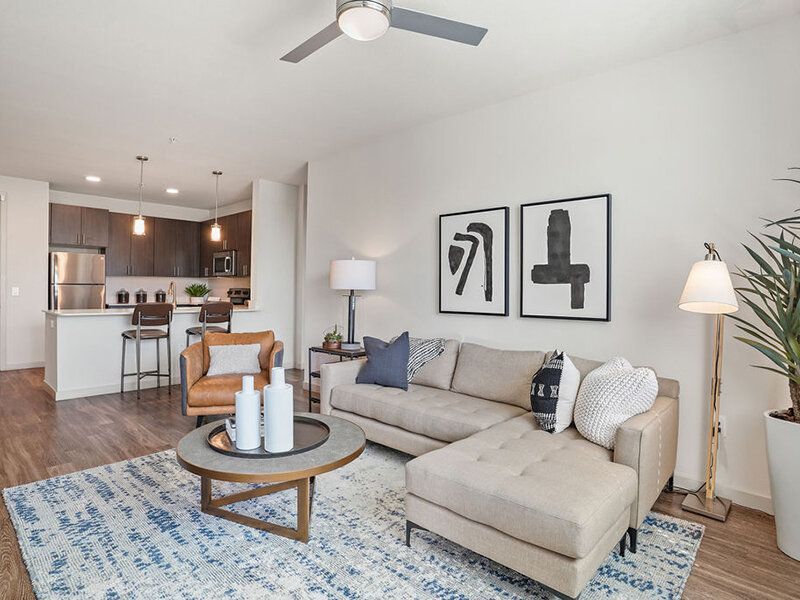 Living room in a modern apartment with a beige sofa, an armchair, and a round coffee table.