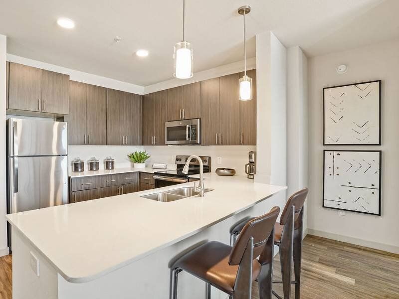 Open-concept kitchen with a white island, stainless steel appliances, and bar stools.