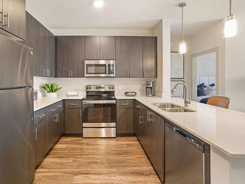 Modern kitchen with dark wood cabinets, stainless steel appliances, and an island.