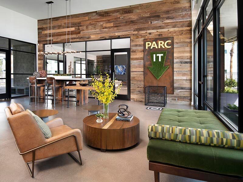 Modern apartment lobby with wood accent wall, seating area, and PARC IT sign.
