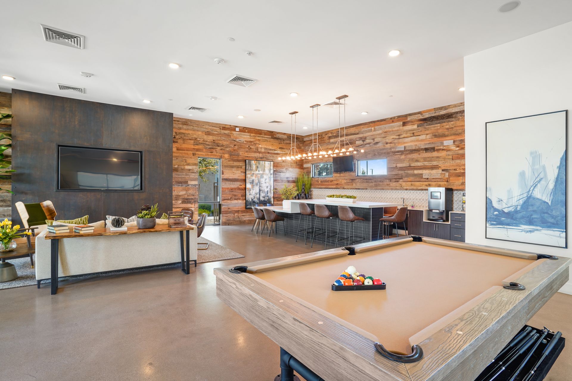 Game room with pool table, kitchen, and TV. Rustic wood and neutral colors at Parc South Mountain in Phoenix, AZ..