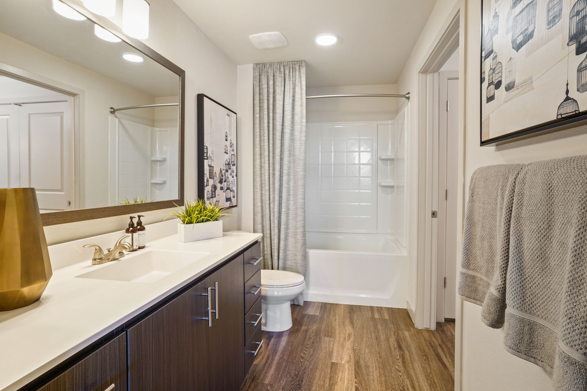 Modern bathroom with a long vanity, white countertop, and wood-look flooring at Parc South Mountain in Phoenix, AZ..