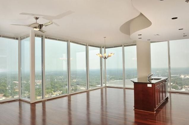 A large empty room with lots of windows and a ceiling fan