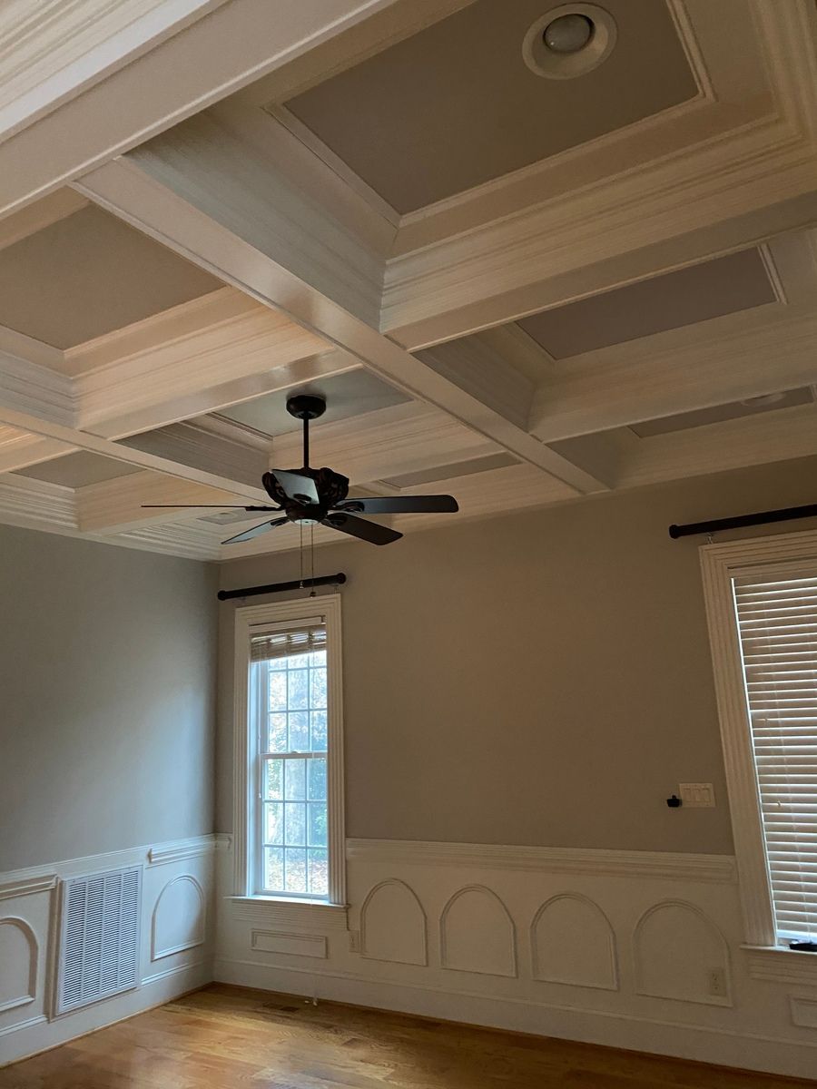 A room with a coffered ceiling and a ceiling fan.
