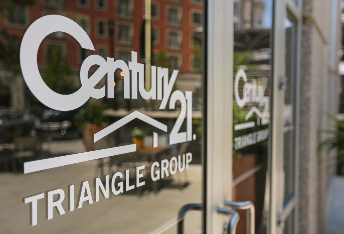 A century 21 triangle group sign is on a glass door
