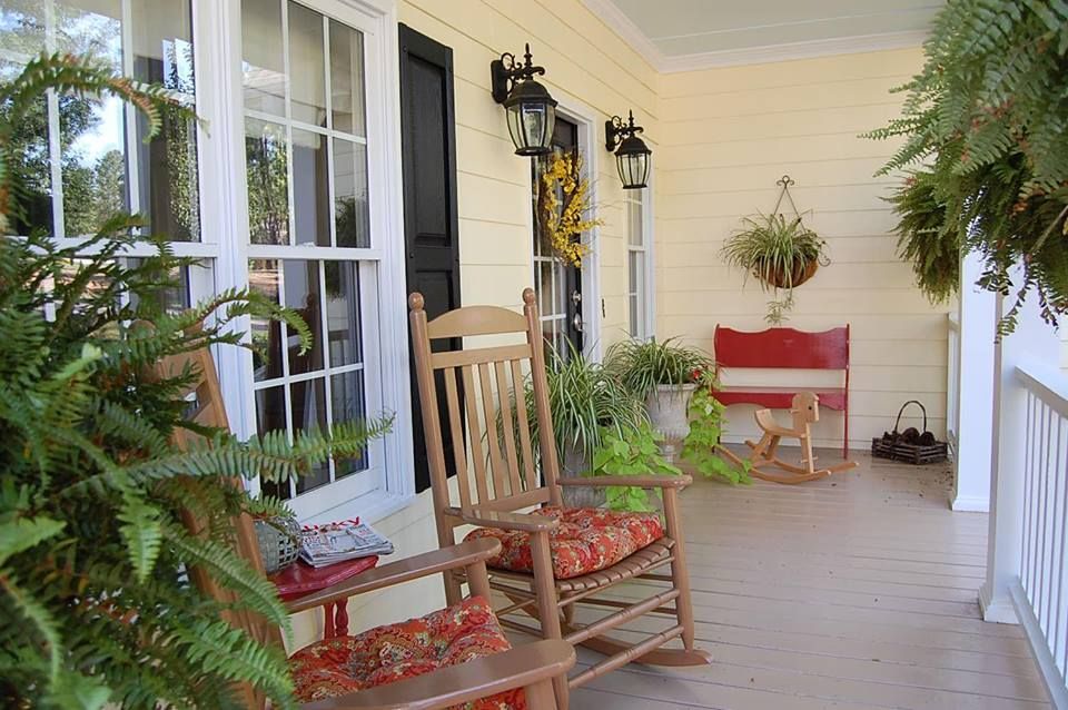 Two rocking chairs are sitting on a porch next to a window.