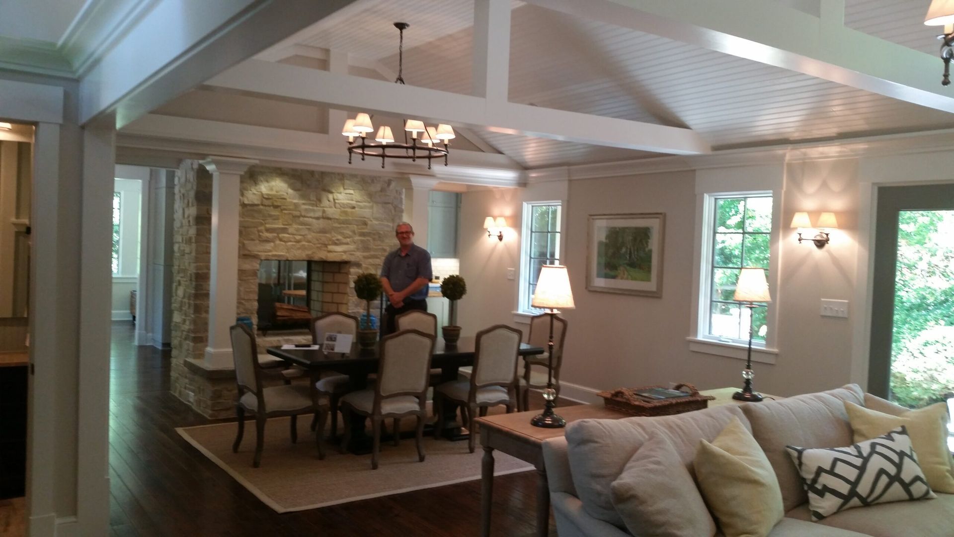 A man is standing in a living room next to a dining room table.