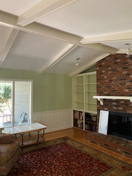 A living room with a brick fireplace and a rug.