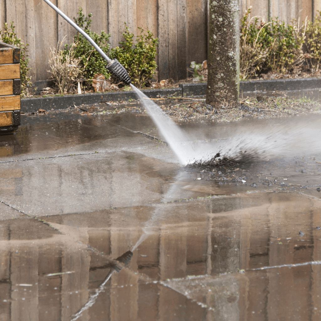 Pressure washer cleaning a brick patio, splashing water.