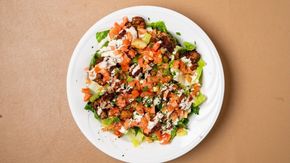 A white plate topped with a salad of vegetables on a table.