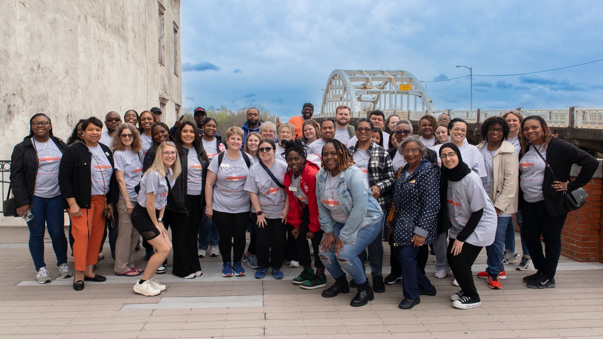 A large group of people are posing for a picture in front of a bridge.