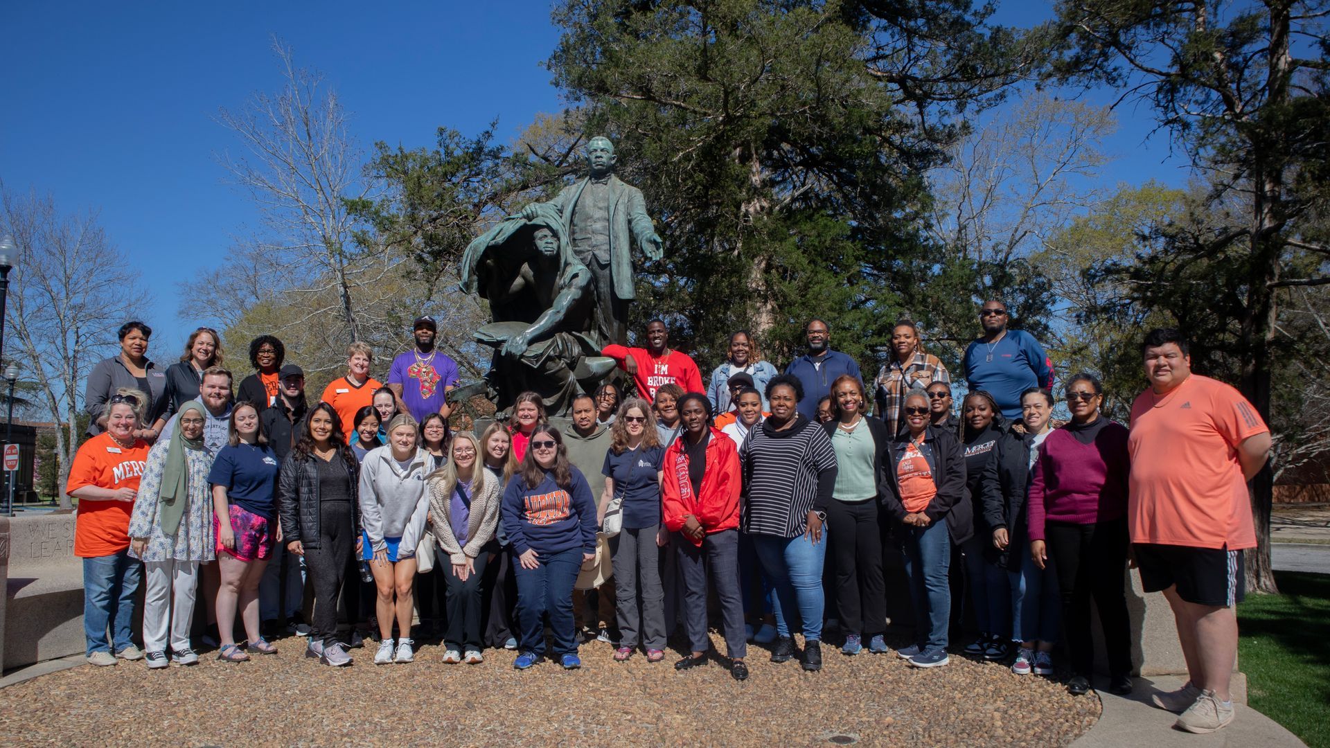 A group of people are posing for a picture in front of a statue.