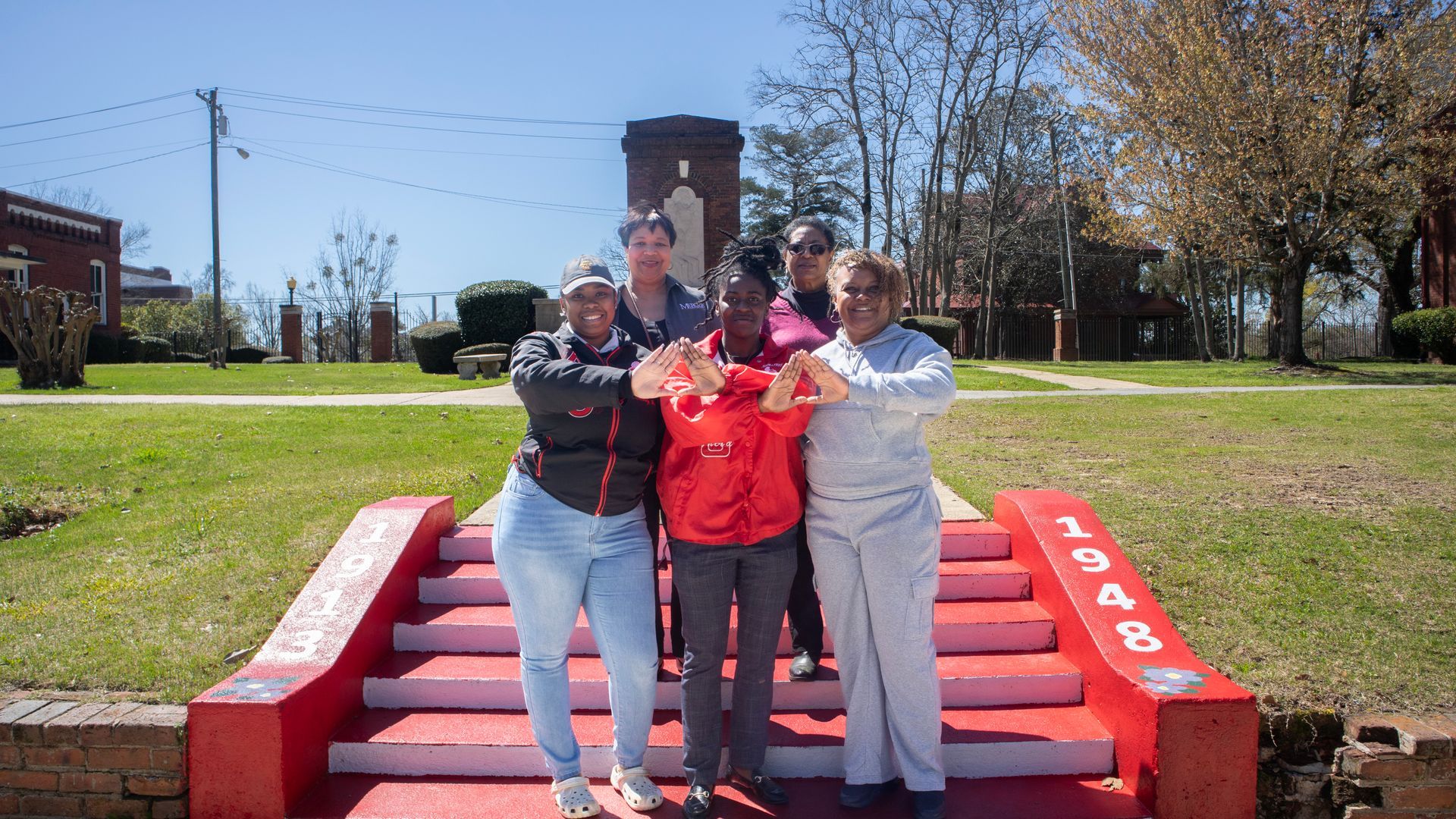 A group of people are posing for a picture on a set of red and white stairs.