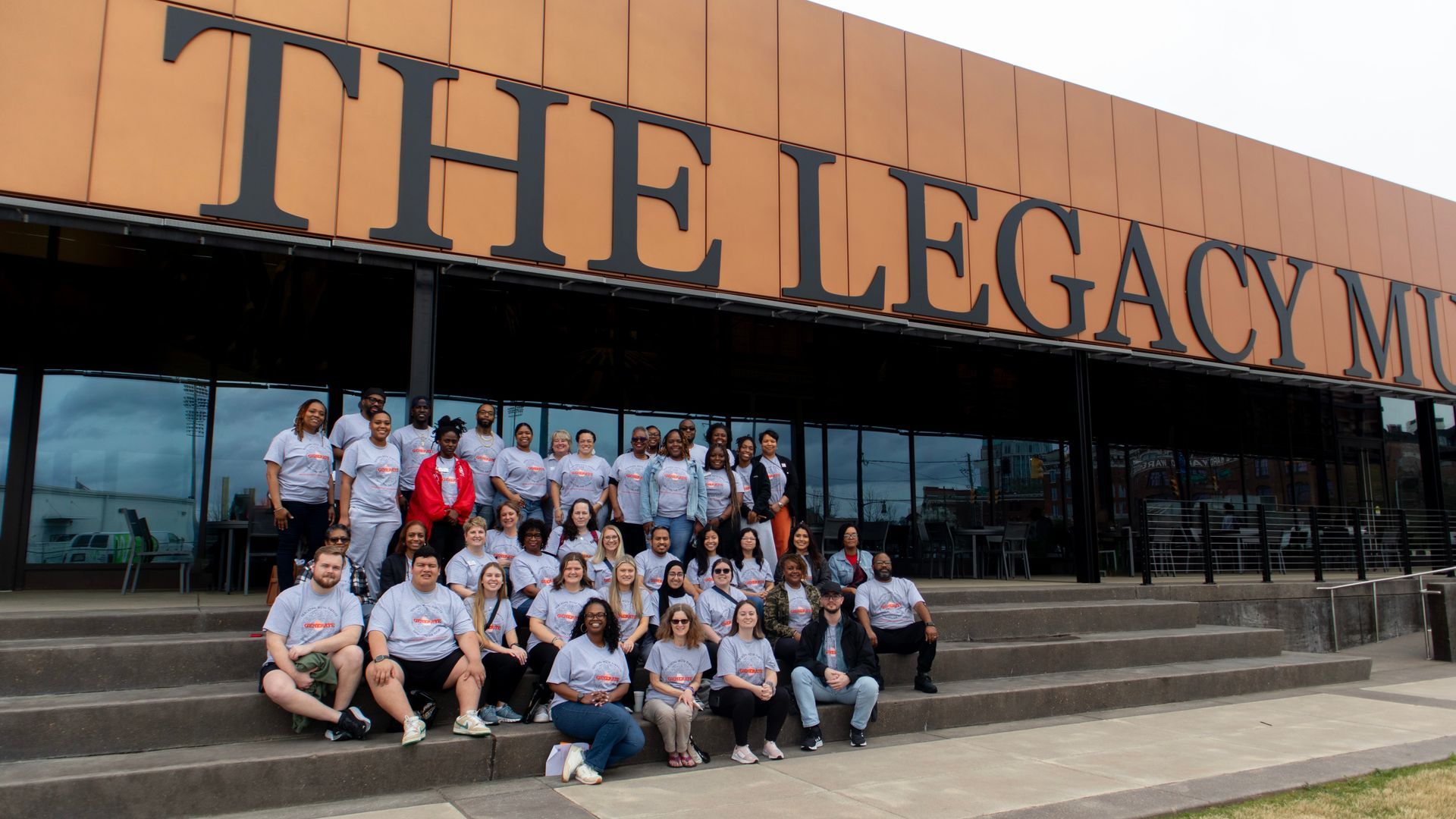 A group of people are posing for a picture in front of the legacy museum.