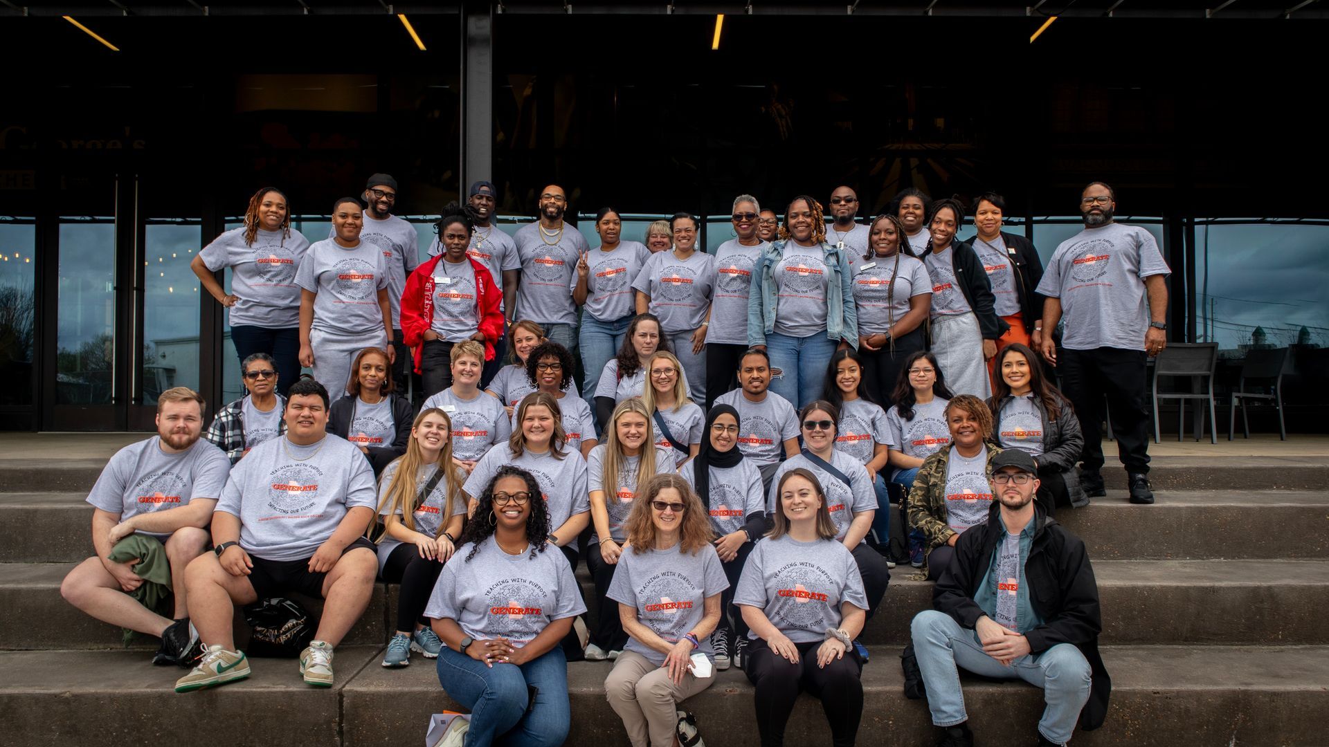 A large group of people are posing for a picture on the steps of a building.