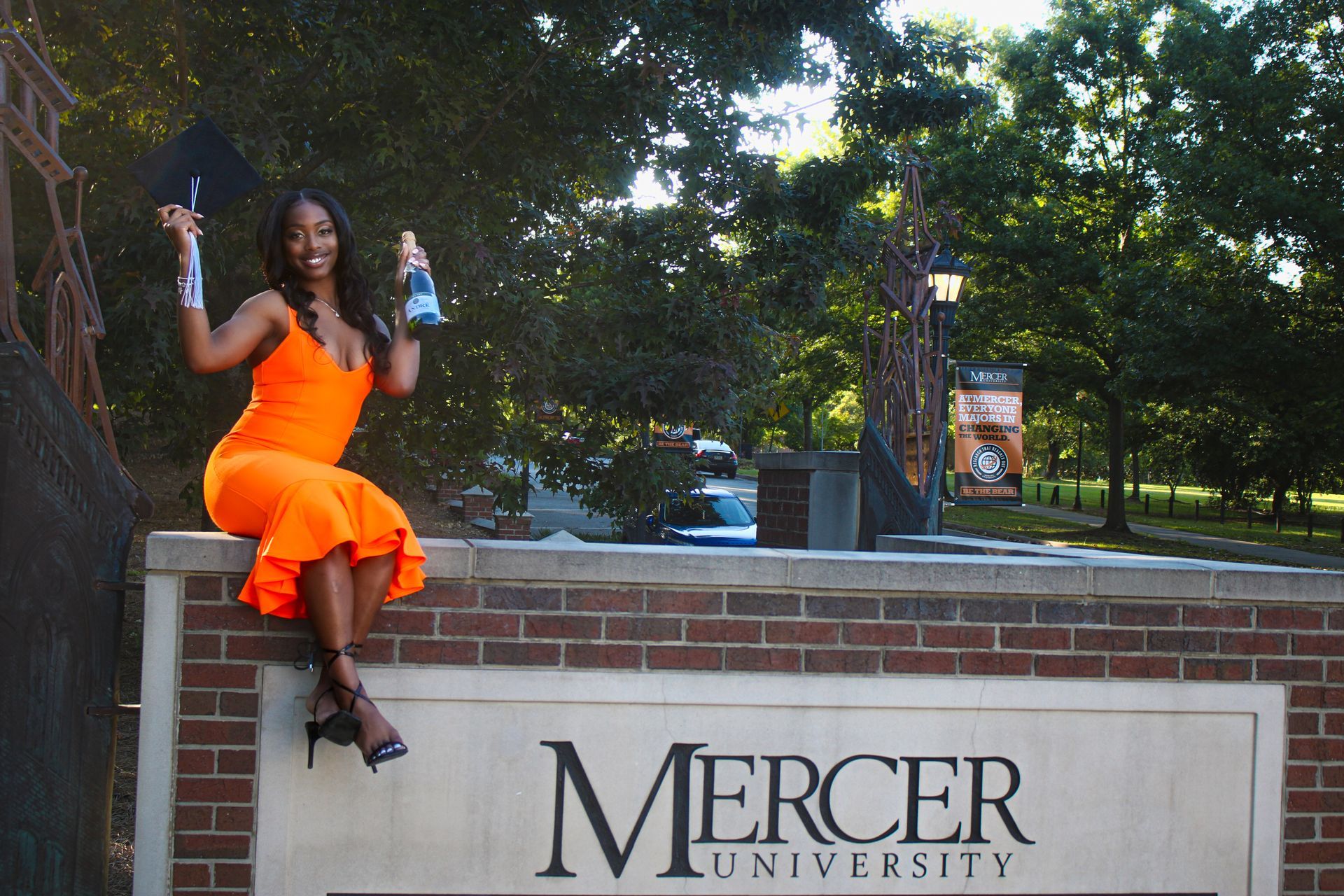 A woman in an orange dress is sitting on a sign for mercer university