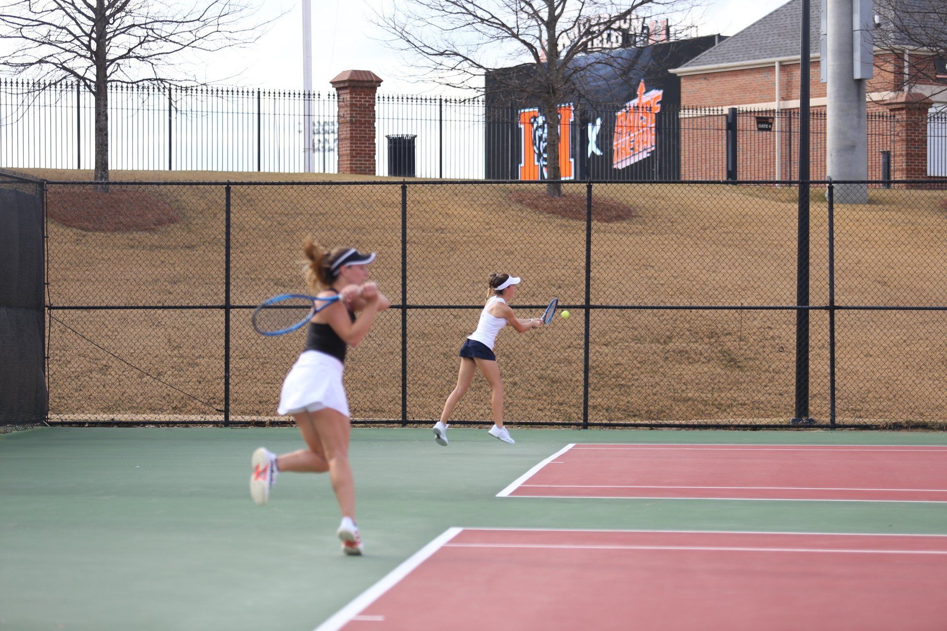 Two women are playing tennis on a tennis court.