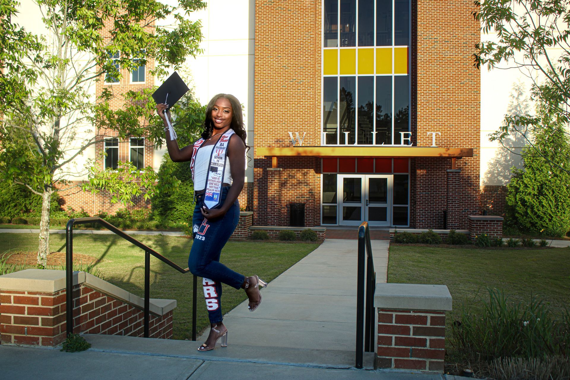A woman is holding a diploma in front of a brick building