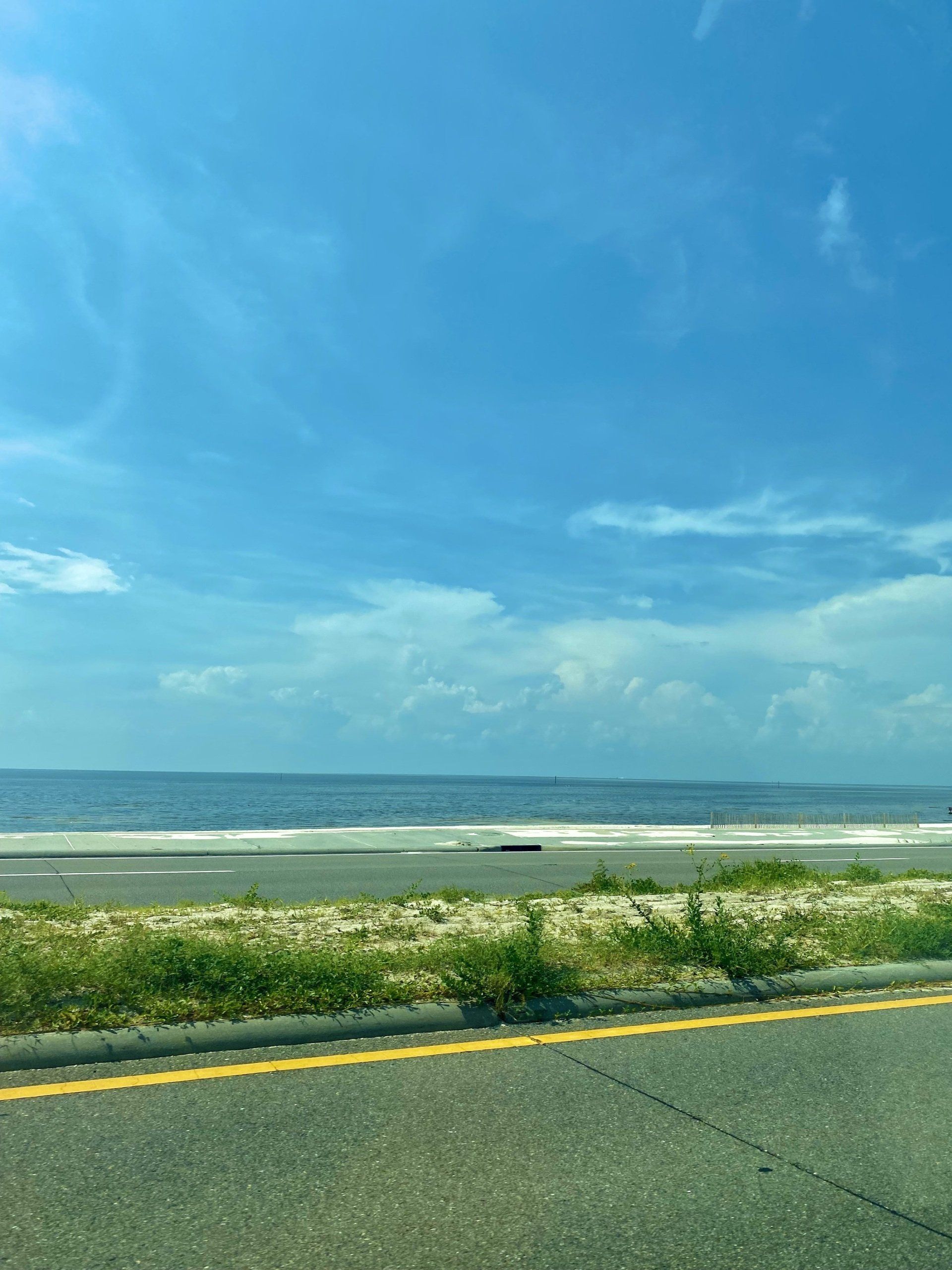 A view of the ocean from a highway on a sunny day.